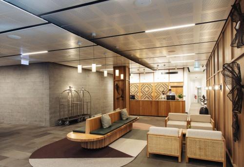 a lobby with a waiting area with a bench and chairs at Sudima Queenstown Five Mile in Queenstown