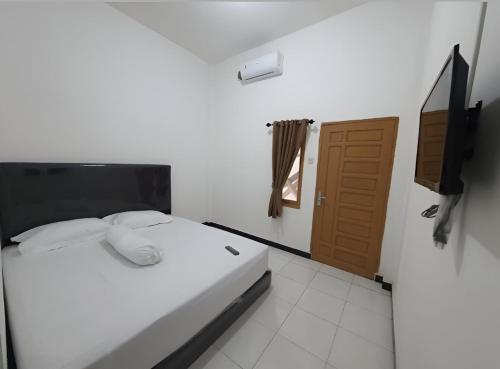 ein Schlafzimmer mit einem Bett, einem TV und einer Tür in der Unterkunft OYO 93306 Homestay Permana Supadio Airport in Pontianak