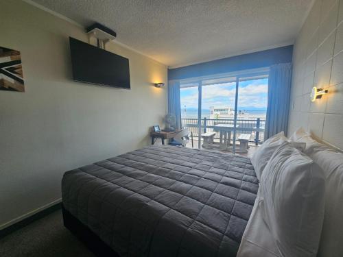 a bedroom with a bed and a view of the ocean at Tui Oaks Motel in Taupo