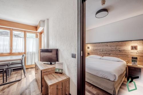 1 dormitorio con 1 cama y 1 mesa con TV en HOTIDAY Apartment Collection - La Thuile, en La Thuile