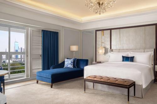 1 dormitorio con 1 cama grande y 1 silla azul en The St. Regis Jakarta en Yakarta