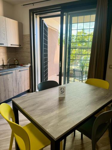 a dining room table with yellow chairs in a kitchen at Suites Dreams Fiumicino River in Fiumicino