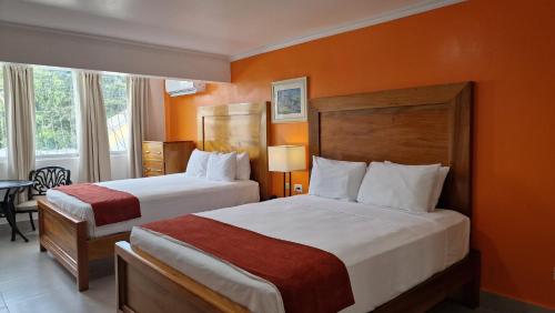 duas camas num quarto de hotel com paredes cor de laranja em Pirate's Inn em Bridgetown