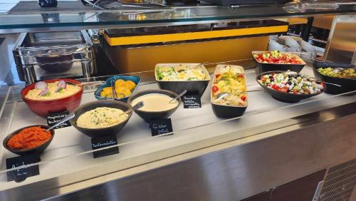 un buffet avec différents types de nourriture dans des bols dans l'établissement Gokart Hotel, à Kecskemét