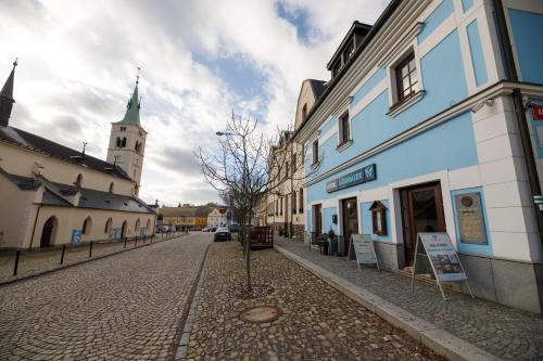 eine Kopfsteinpflasterstraße in einer Stadt mit einem Uhrturm in der Unterkunft Hotel Modrásek in Kašperské Hory