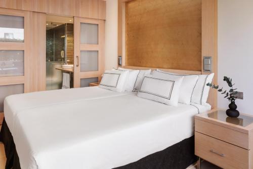 una camera da letto con un grande letto bianco con testiera in legno di Melia Sevilla a Siviglia