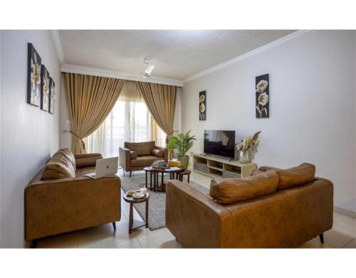 sala de estar con 2 sofás y TV en Marjaan Apartments, en Mombasa