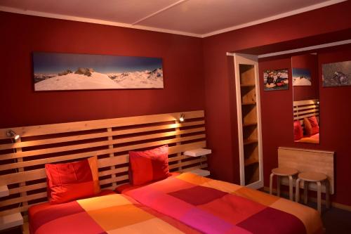 una camera da letto con pareti rosse e un letto con cuscini rossi di Adventure Hostel a Klosters