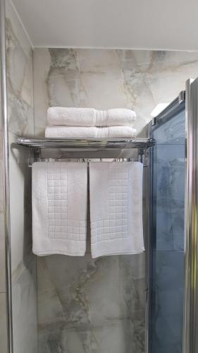 a bathroom with white towels on a rack at Dei Cozy Apartment in Shkodër