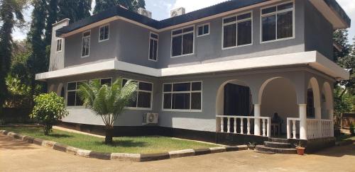 une grande maison avec un palmier en face dans l'établissement White Lodge Moshi, à Moshi