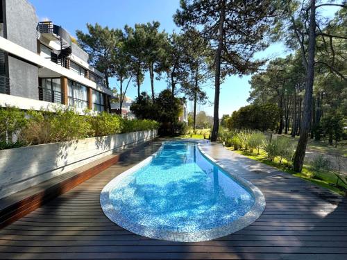 - une piscine sur une terrasse en bois à côté d'un bâtiment dans l'établissement Departamento Premium con Piscina y Cochera, à Pinamar