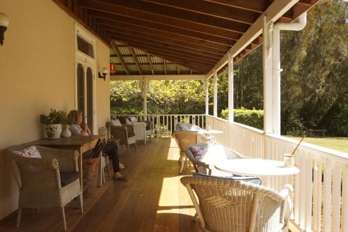 una veranda con tavoli e sedie su una terrazza di The Carriages Boutique Hotel and Vineyard a Pokolbin