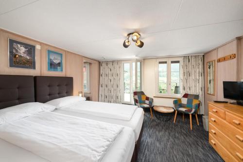 een hotelkamer met 2 bedden en een televisie bij Jungfrau Lodge, Swiss Mountain Hotel in Grindelwald