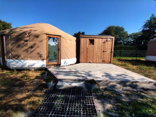 uma tenda com uma porta de madeira num campo em Le camélia em Brugelette