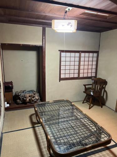 a room with a bed and a chair and a window at 一日限定一組の宿なんでもん in Naoshima