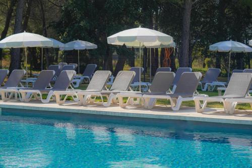 a group of lounge chairs and umbrellas next to a pool at Grand Prix Hôtel & Restaurant in Le Castellet