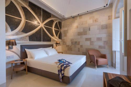 ein Hotelzimmer mit einem Bett und einem Stuhl in der Unterkunft Maniace Boutique Hotel Ortigia | UNA Esperienze in Syrakus