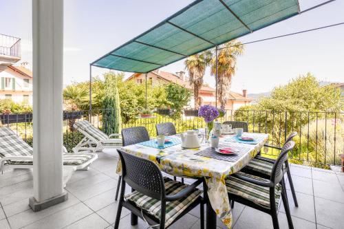 een tafel en stoelen op een patio met een parasol bij Appartamento Gino in Cannero Riviera