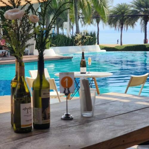 two bottles of wine sitting on a table next to a pool at studio room seaview jomtien in Jomtien Beach