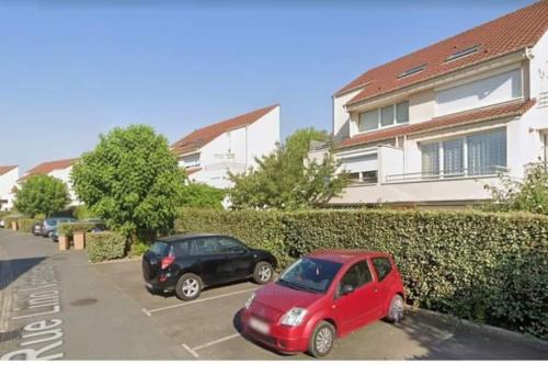 twee auto's geparkeerd op een parkeerplaats voor een gebouw bij Appartement de 51 m2 avec jardin de 51 m2, parking privé in Achères