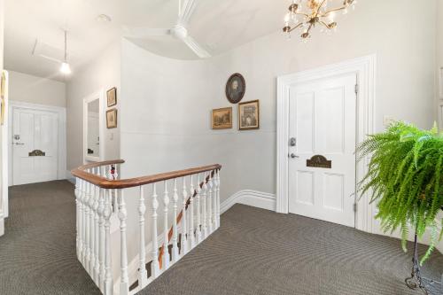 a white room with a staircase and a clock on the wall at The 1885 Suites in Picton