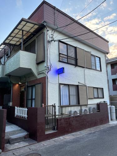 浦安URAYASU HOUSE! for up to 6 people, 15 min bus ride to Disney! Location is 6-8-38 Horie Urayasu City Chiba Prefecture 場所は千葉県浦安市堀江6-8-38です,玄関横のキーボックスの暗証番号はご予約後に宿からのメッセージ欄にてご確認下さい的前面有蓝色标志的白色房子