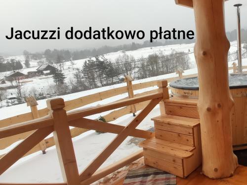 una terraza de madera con bañera de hidromasaje en la nieve en Góralskie Domki na Podhalu - z jacuzzi, en Maniowy