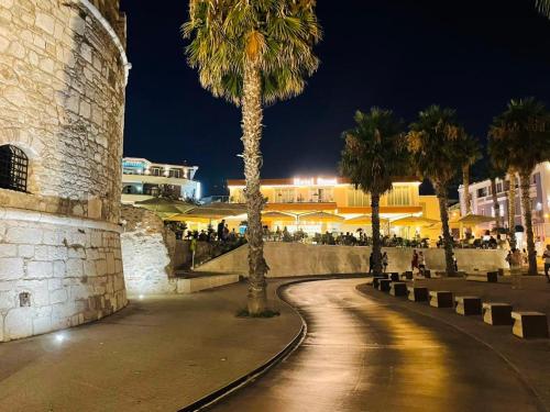 een straat met palmbomen en 's nachts een gebouw bij Bizant Boutique Hotel & Coffee,Bar in Durrës