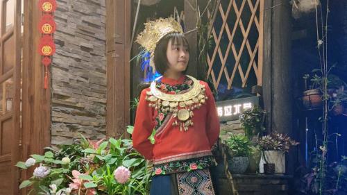 Ein junges Mädchen in einem traditionellen Kleid steht im Garten in der Unterkunft Breeze & Alley Inn---Provide journey planning and ticket bookìng services in Zhangjiajie