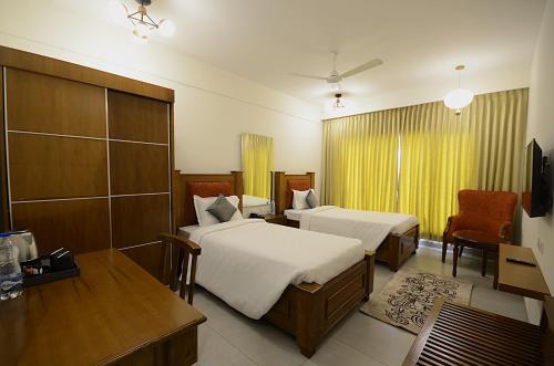 Habitación de hotel con 2 camas y escritorio en Eka Lyf Inn, en Coimbatore