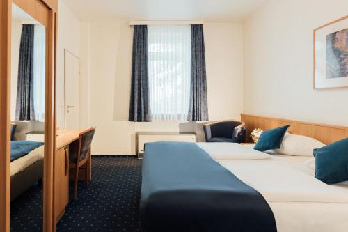 um quarto de hotel com três camas e uma secretária em Hotel Commerz Hamburg em Hamburgo