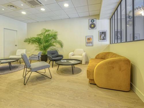 Sala de espera con sofá, sillas y mesa en ibis Cholet, en Cholet