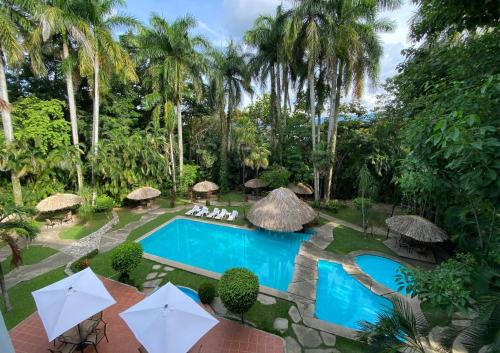 einen Luftblick auf einen Resortpool mit Sonnenschirmen in der Unterkunft Hotel Maya Palenque in Palenque