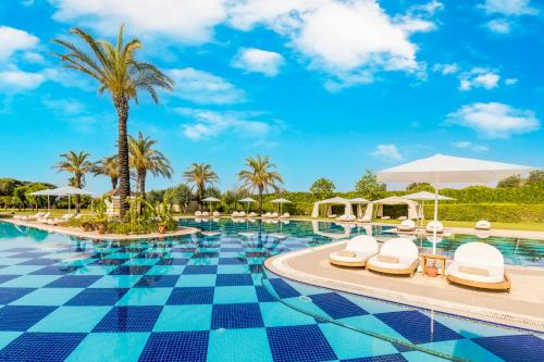 uma piscina num resort com cadeiras e palmeiras em Kempinski Hotel The Dome Belek em Belek