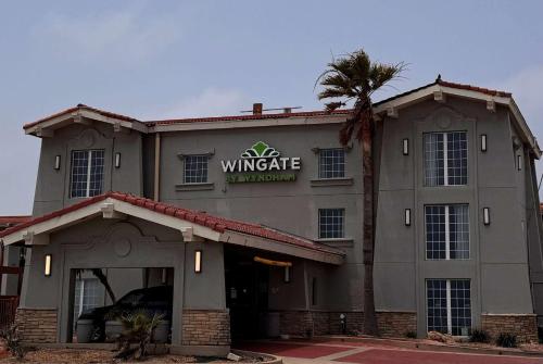 um edifício vinícola com uma palmeira em frente em Wingate by Wyndham Galveston East Beach em Galveston