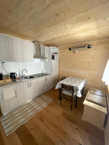 uma cozinha com uma mesa e um lavatório num quarto em Nido Ampezzano em Borca di Cadore