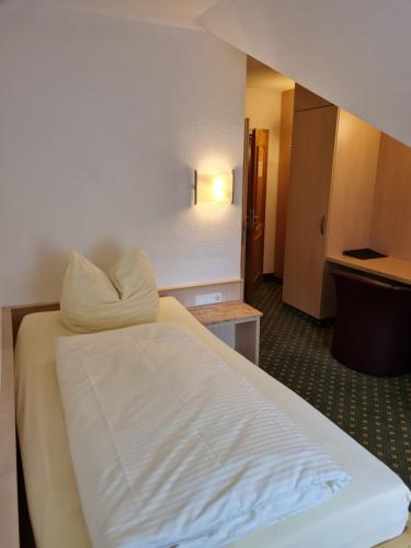 um quarto de hotel com uma cama com lençóis brancos em Hotel Stolberg em Wiesbaden