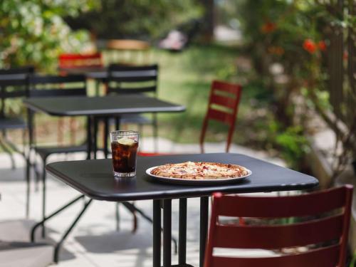 una pizza sentada en una mesa con una bebida en ibis Lyon Carre De Soie, en Vaulx-en-Velin