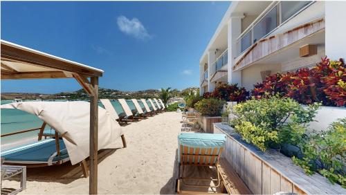 eine Reihe von Stühlen und Sonnenschirmen an einem Strand neben einem Gebäude in der Unterkunft Hotel Les Ondines Sur La Plage in Gustavia