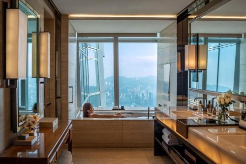 uma mulher numa banheira numa casa de banho com vista em The Ritz-Carlton Hong Kong em Hong Kong