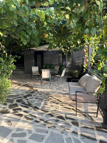 a patio with couches and chairs under a tree at Apartment Lui in Tbilisi City