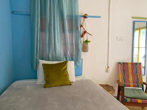 een blauwe slaapkamer met een bed met een geel kussen bij Nómade in San Juan La Laguna