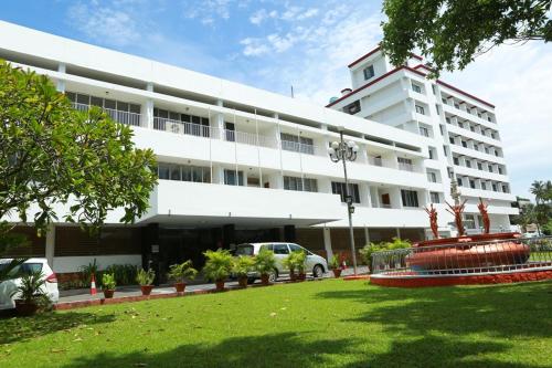 um grande edifício branco com um relvado em frente em Casino Hotels Ltd em Thrissur