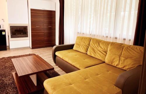 a living room with a yellow couch and a table at Silver Mountain, Poiana Brasov - Forest Crib in Braşov