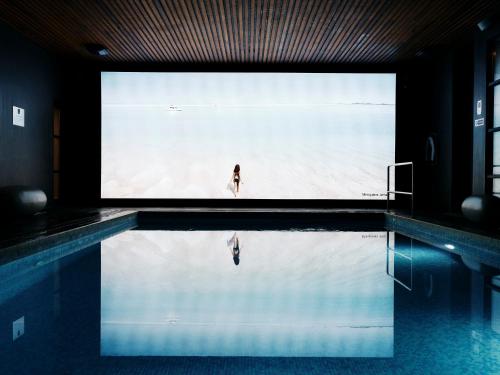 a woman standing in a swimming pool with a large screen at The Club Hotel & Spa Jersey in Saint Helier Jersey