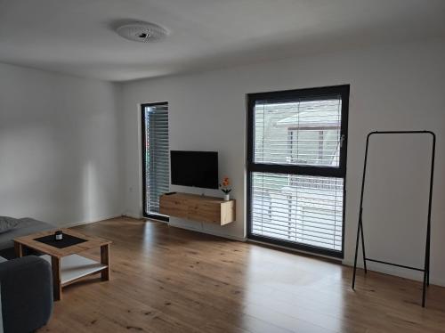 sala de estar con TV de pantalla plana y 2 ventanas en B&D apartment, en Maribor