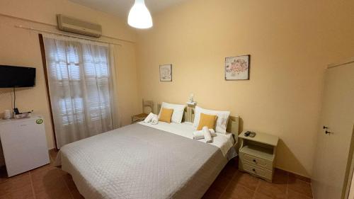 a bedroom with a white bed and a television at romanza rooms in Poúlithra