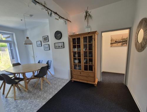 a dining room with a table and chairs and a cabinet at Gästehaus bed & kitchen in Schleswig