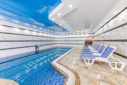 - une piscine avec 2 chaises longues à côté de la piscine dans l'établissement Hotel Bellavista & Spa, à Bukovel