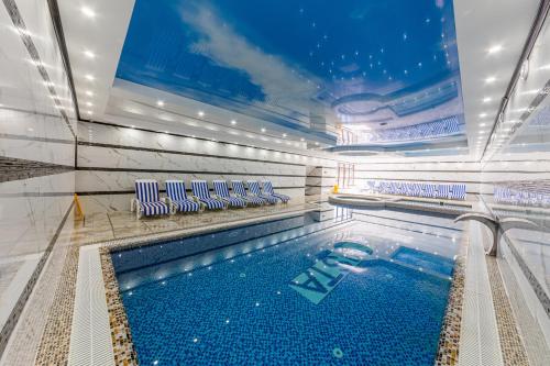 - une piscine avec des chaises bleues et blanches dans un bâtiment dans l'établissement Hotel Bellavista & Spa, à Bukovel